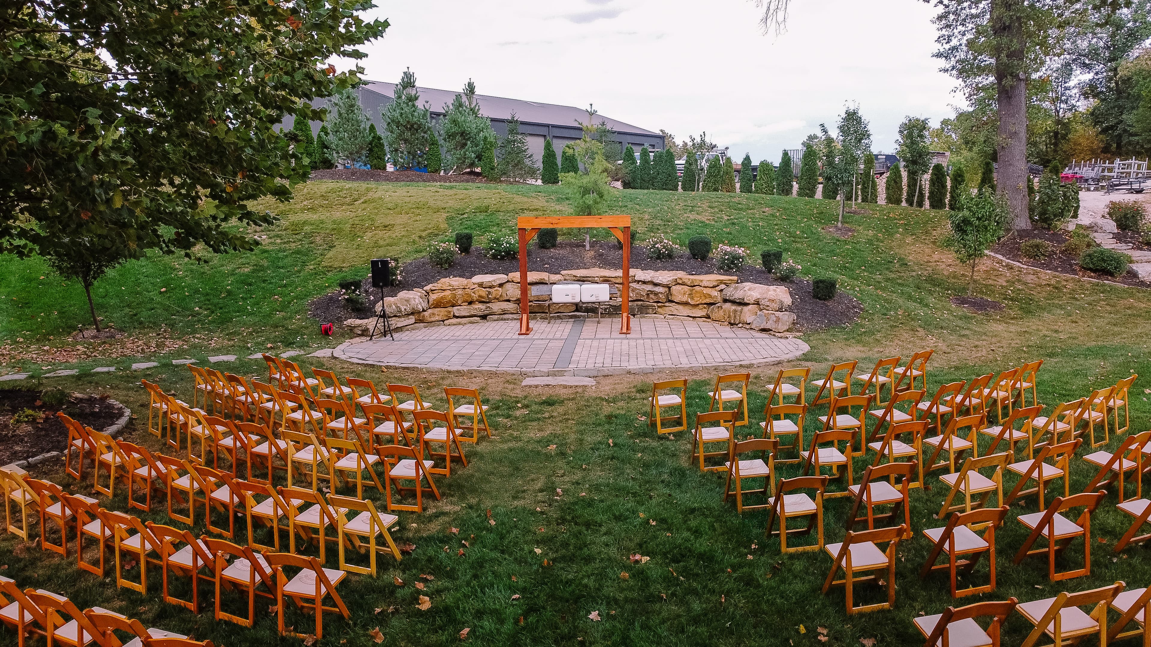 Outdoor ceremony space with wooden chairs and arbor