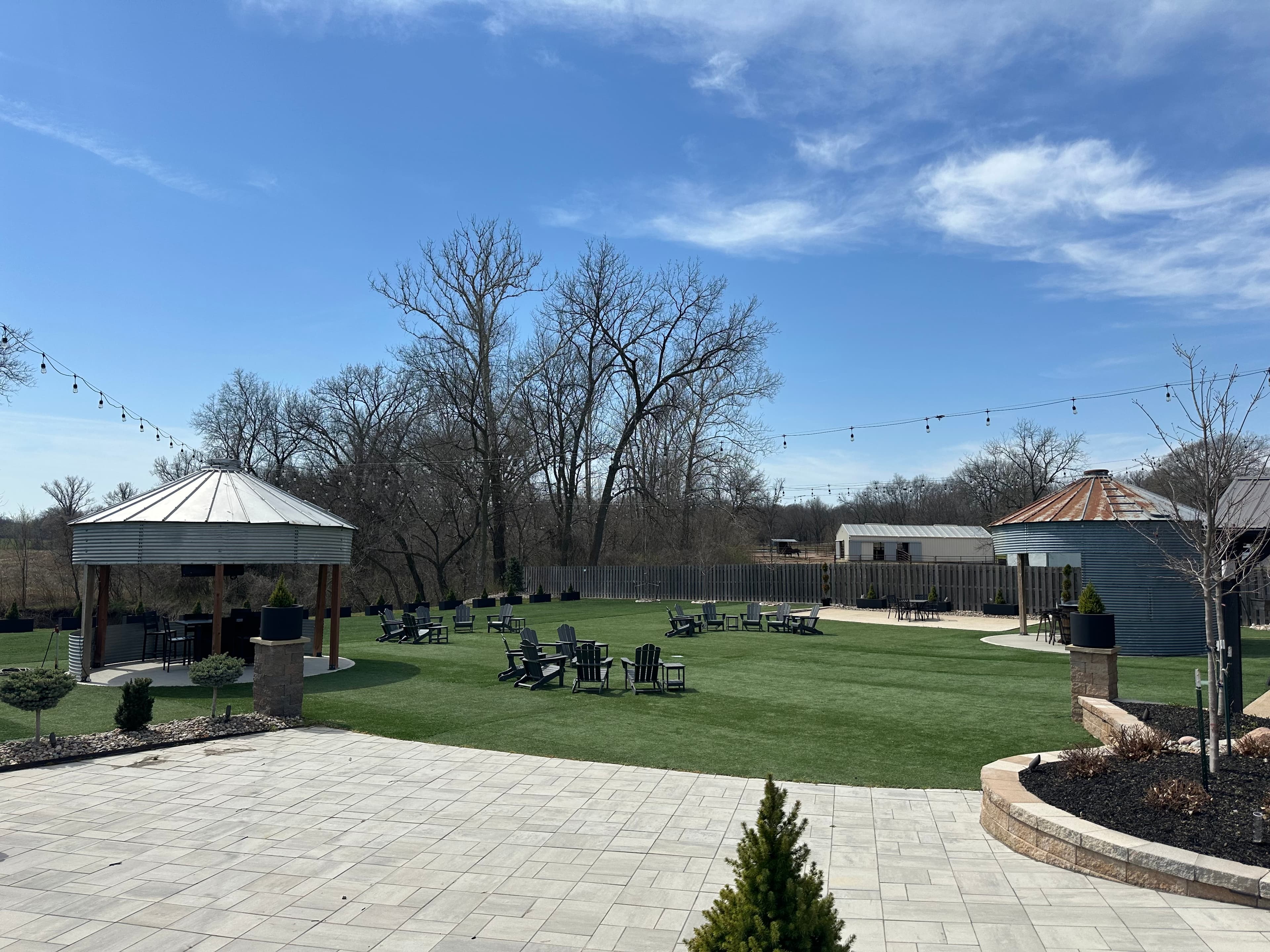 Outdoor venue grounds with gazebo, lawn seating, and string lights